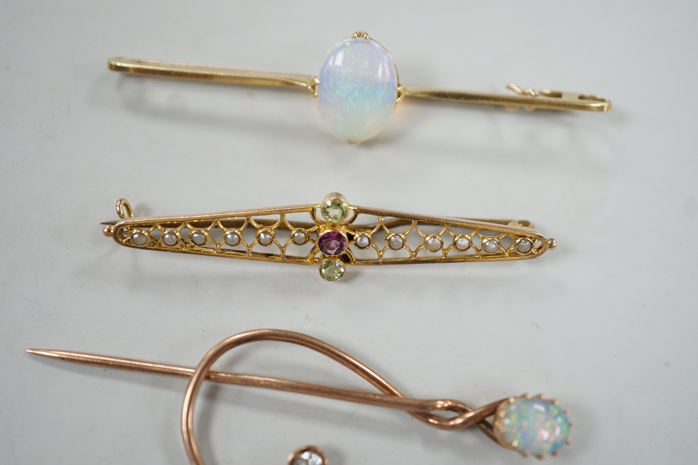 A novelty yellow metal, white opal and diamond set 'treble clef' stick pin, 60mm, a 15ct and white opal set bar brooch and one other 9ct and gem set brooch, gross weight 8.2 grams.